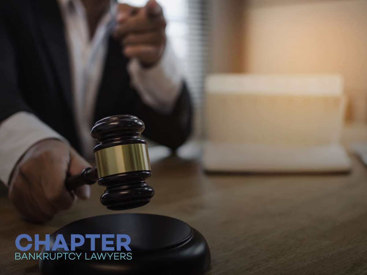 Close-up of a gavel in the hand of a bankruptcy attorney, with the text 'Chapter Bankruptcy Lawyers' superimposed, indicating their specialization.