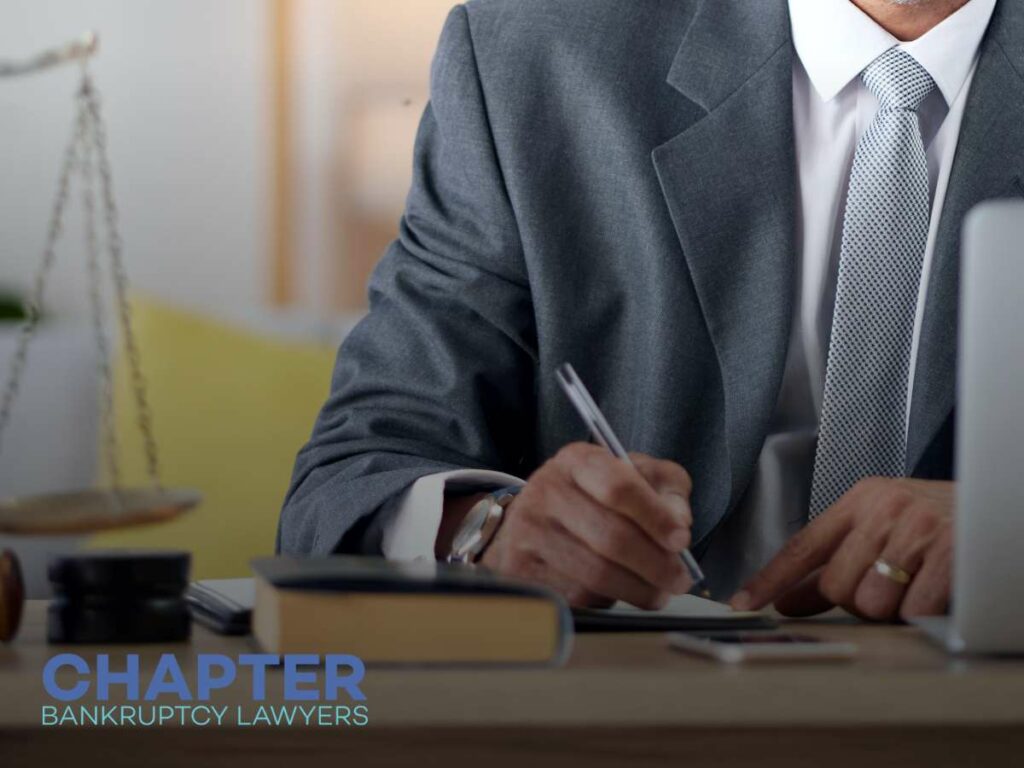 A bankruptcy lawyer in a suit reviewing legal documents at a desk with a scale and gavel nearby